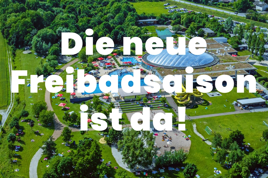 Das Bild zeigt die Drohnenaufnahme des Schwimmbads mit Außenbecken, Rutsche und Liegewiese und den Schriftzug 'Die neue Freibadsaison ist da!'.